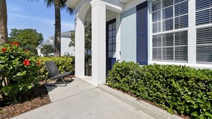 A residential house with a covered porch, a chair, and a well-maintained hedge. - Lake View End Unit Town Home Closest to ALL of the Amenities at WINDSOR HILLS (Kissimmee)