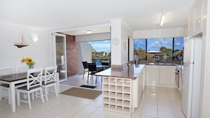 A modern kitchen with white cabinets, a built-in island, and a large window offering a view of the outdoors.