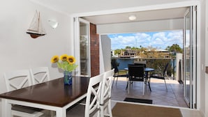 A balcony with a dining table, chairs, and a vase with sunflowers.
