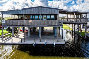 A two-story waterfront building with a dock, a sign for rent, and a view of the water.