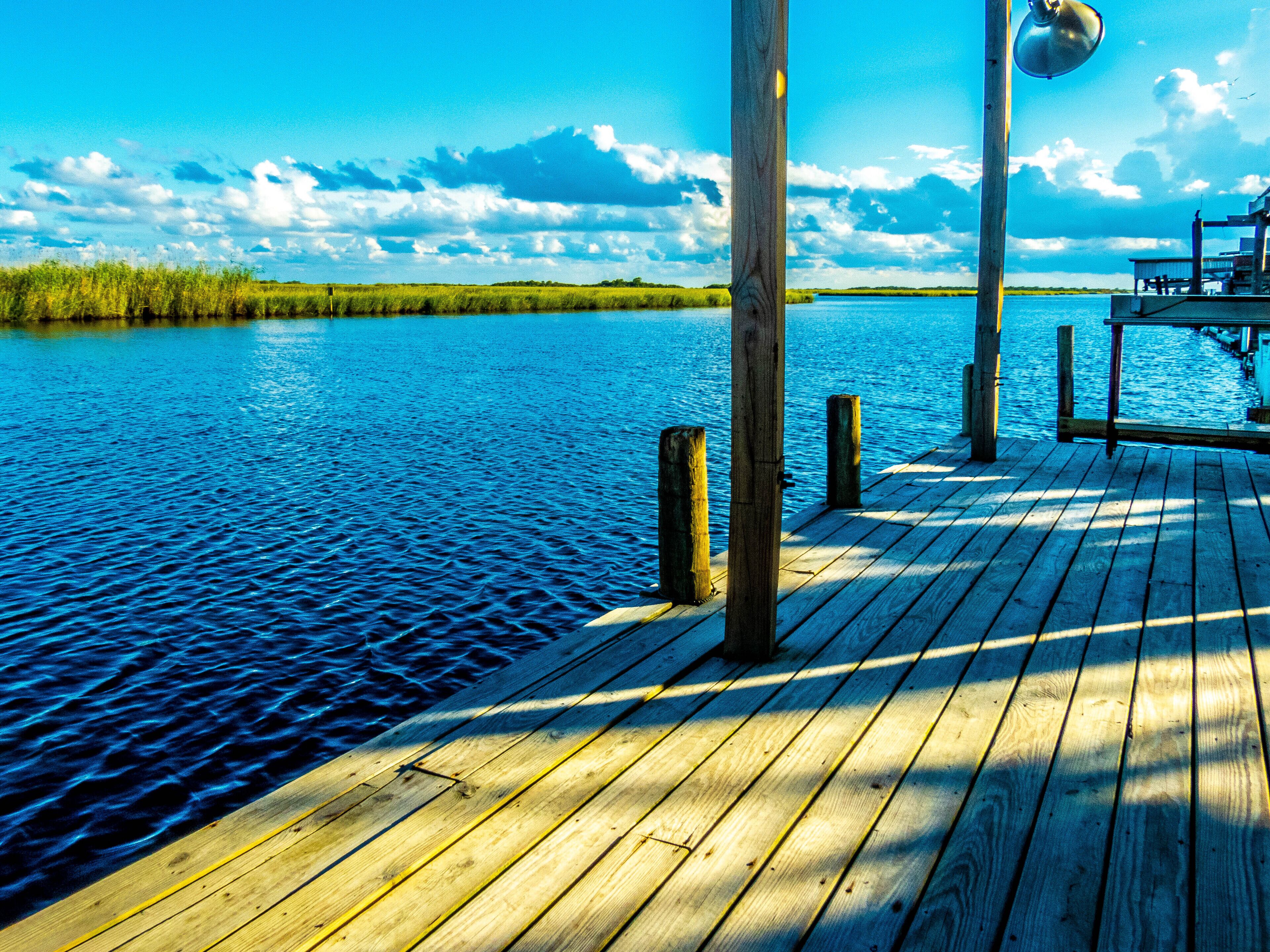 A wooden dock extending into a calm body of water with a clear sky above.