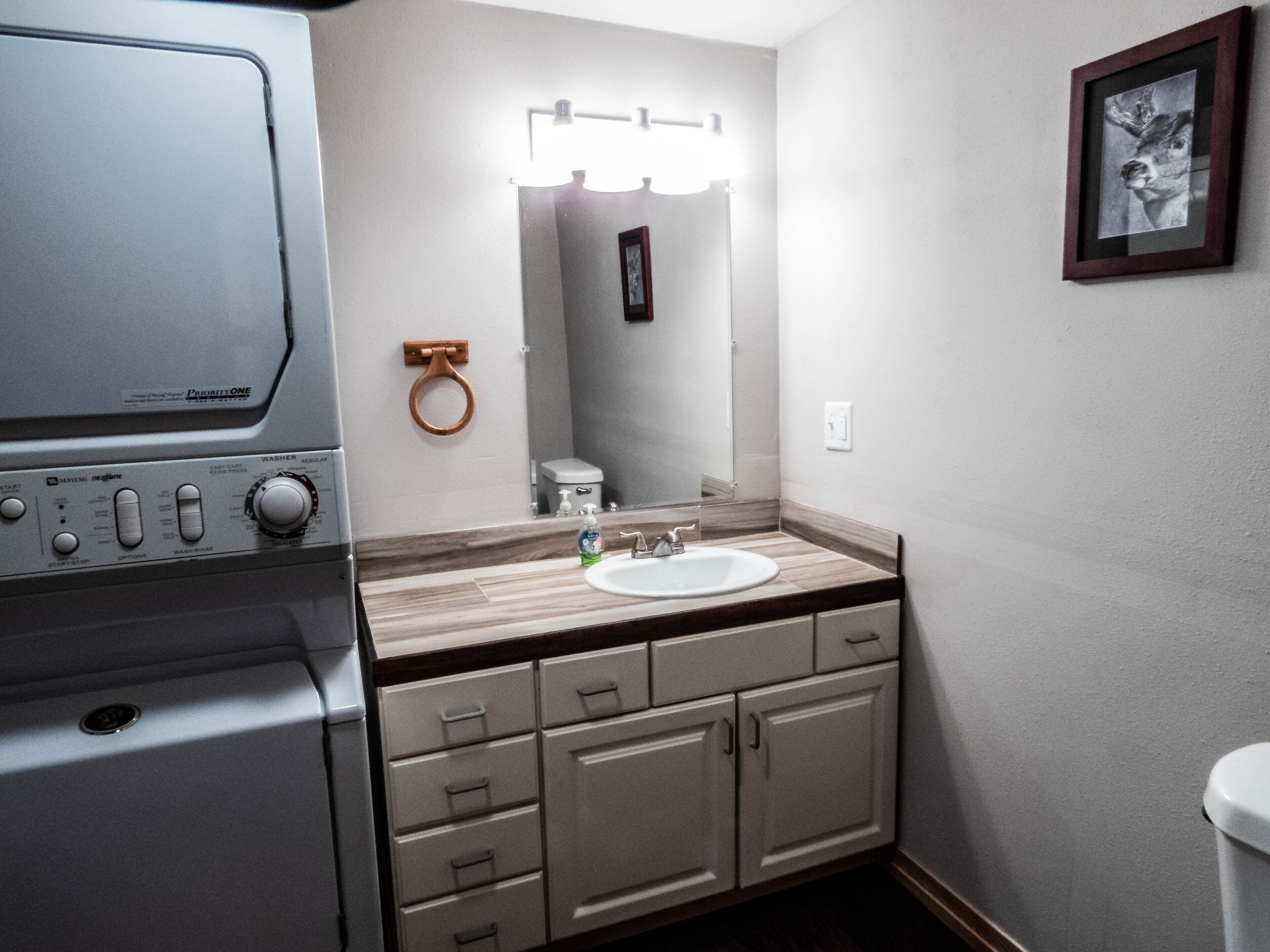 A compact bathroom with a sink, mirror, and a wall-mounted toilet.