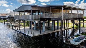 A waterfront house with a dock, outdoor seating, and a covered patio.