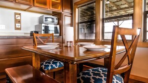 A wooden dining table with chairs, a bench, and a microwave above it.