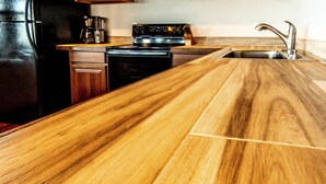 A kitchen with a wooden countertop, a stove, a dishwasher, and a sink.