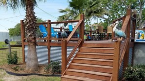 A wooden staircase leading to a deck area with a palm tree and a birdhouse. -  Reel'em Inn - Adventures Start Here! (Port O'Connor)