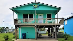 A two-story building with a balcony, a garage, and a fenced area. -  Reel'em Inn - Adventures Start Here! (Port O'Connor)