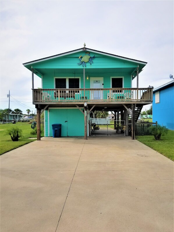 A two-story building with a balcony, a garage, and a fenced area. - Reel'em Inn - Adventures Start Here! (Port O'Connor)