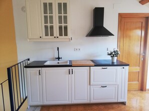 Efficient kitchen with a single sink, modern faucet, and black range hood.