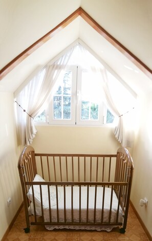 Cozy retreat with a sloped ceiling, wooden crib, and serene view of the snowy landscape.