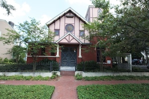 A two-story building with a symmetrical facade, a central entrance with a black door, and a small circular window above the door. - The Bell Tower Loft at Sanctuary Place (Savannah)