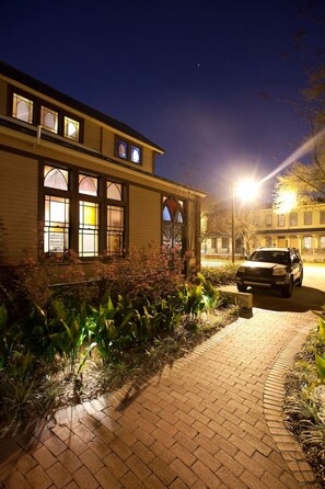 A building with a brick pathway leading to a car parked in front.