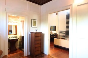 A hallway with a wooden cabinet, a framed picture on the wall, and a sofa in the adjacent room.