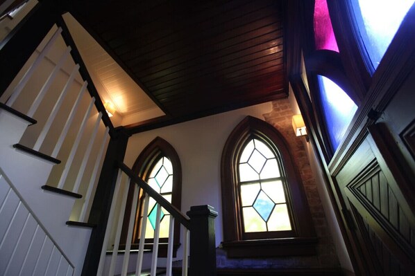 A staircase with wooden railings and stained glass windows. - The Bell Tower Loft at Sanctuary Place (Savannah)
