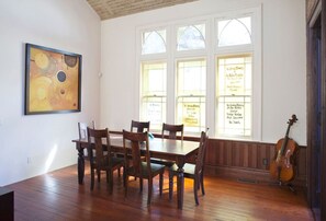 A dining area with a wooden table and chairs, a violin, and a painting on the wall.