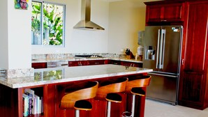 A kitchen with a large island, bar stools, a stainless steel refrigerator, and wooden cabinets. - Villa Bella Vista:  Views, Privacy & Beach Proximity, We Have It All Right Here (manuel antonio)