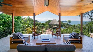 A wooden deck with a thatched roof, two wooden chairs, a sofa, and a table with a magazine. - Villa Bella Vista:  Views, Privacy & Beach Proximity, We Have It All Right Here (manuel antonio)