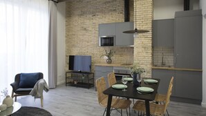 Una cocina moderna con pared de ladrillo, una mesa de comedor con platos y vasos, y un televisor sobre un mueble.