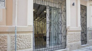 Fachada de edificio con una reja de hierro forjado y un muro de piedra.