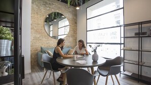 Un interior moderno con pared de ladrillo, un espejo redondo y un ventanal con vistas a edificios.