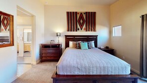 A bedroom with a large bed, a nightstand, a dresser, and a wall-mounted artwork. - Cairn House - 4A7 (Moab)