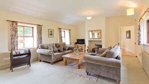 A living room with two sofas, a coffee table, and a television. - Spacious traditional Irish cottage, on the banks of the Boyne. Pet friendly. (Baltray)