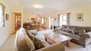 A spacious living room with a sofa set, a coffee table, and a dining area in the background. - Spacious traditional Irish cottage, on the banks of the Boyne. Pet friendly. (Baltray)