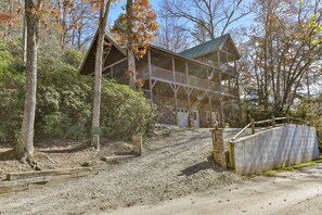 A cabin with a porch and a staircase leading to a second level.