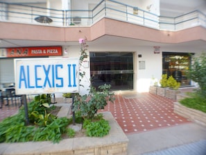 Entrada d'un edifici amb un senyal que diu "ALEXIS II" i un cartell de "Pasta & Pizza" a dalt.