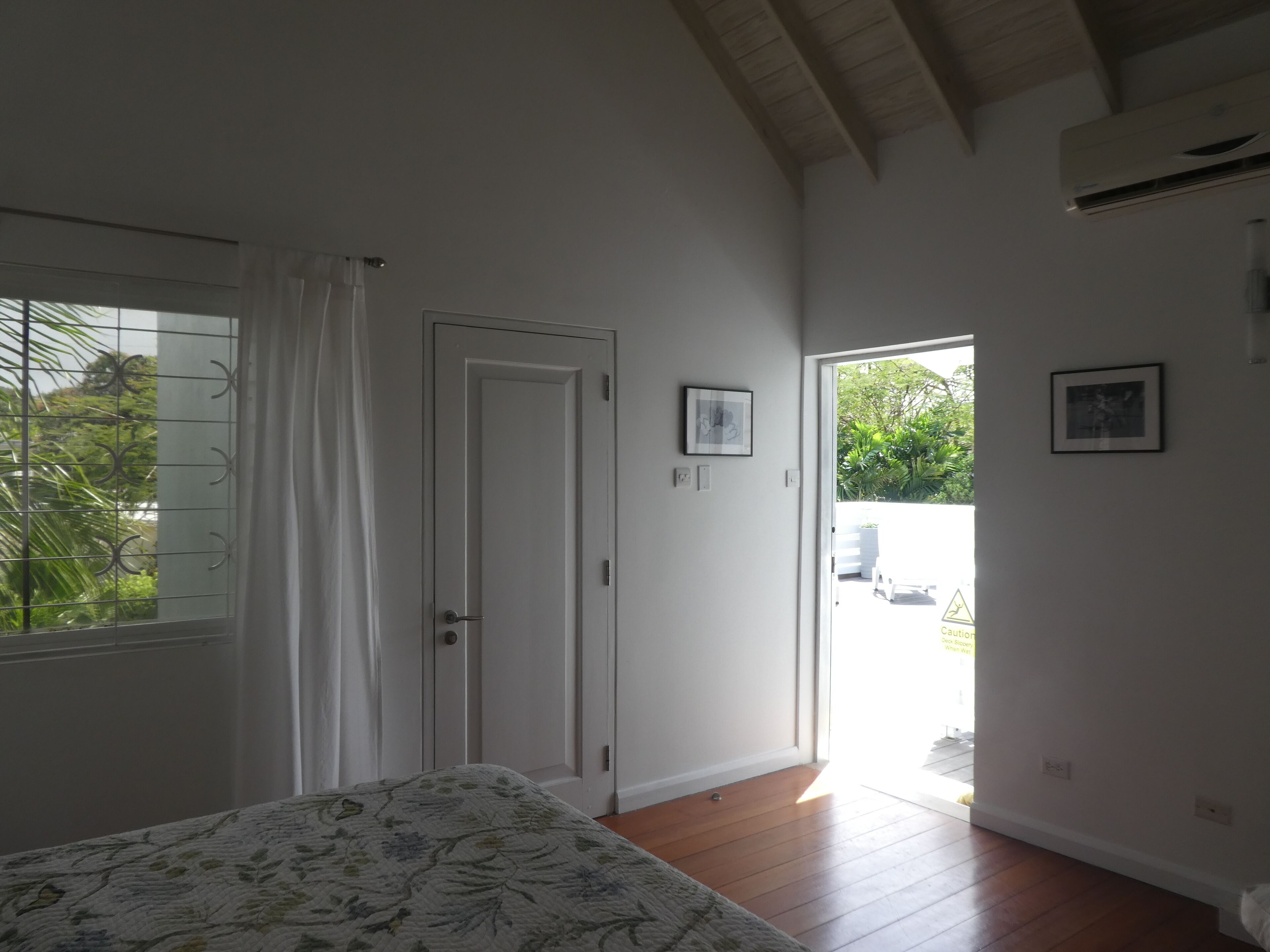 Un dormitorio con cama, una puerta y vistas al exterior.