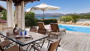 A poolside area with a table, chairs, and an umbrella.