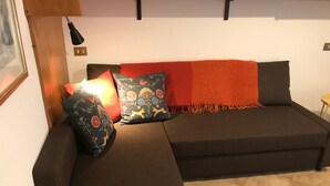 Una sala moderna con un sofá modular, una manta roja y cojines decorativos.