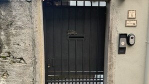 Una reja de metal negro con un buzón, un muro de piedra y una placa pequeña con el número 6.