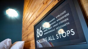 A framed sign with the number 86 and the text "CALLING ALL STOPS" on a wooden wall.