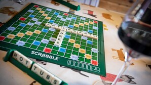 A Scrabble board game with tiles and a glass of wine.