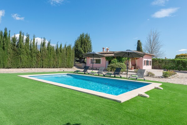 A rectangular swimming pool with a tiled edge, surrounded by a well-maintained lawn.
