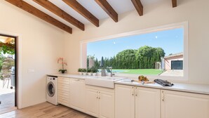 A modern kitchen with a large window, wooden beams, a washing machine, and a sink. - SES VELES - Villa with private pool in Lloseta. (Lloseta)
