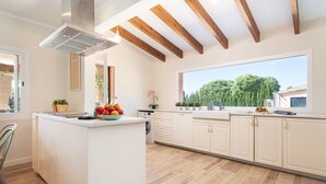 A modern kitchen with wooden beams, a large window, and a fruit bowl on the counter. - SES VELES - Villa with private pool in Lloseta. (Lloseta)