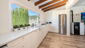 A modern kitchen with white cabinets, a stainless steel refrigerator, and a window with a view of greenery and buildings. - SES VELES - Villa with private pool in Lloseta. (Lloseta)