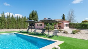 A swimming pool with lounge chairs and umbrellas, surrounded by a well-maintained lawn and a house with a tiled roof. - SES VELES - Villa with private pool in Lloseta. (Lloseta)