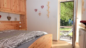 A bedroom with a wooden bed, a small bedside table, and a wall-mounted shelf.
