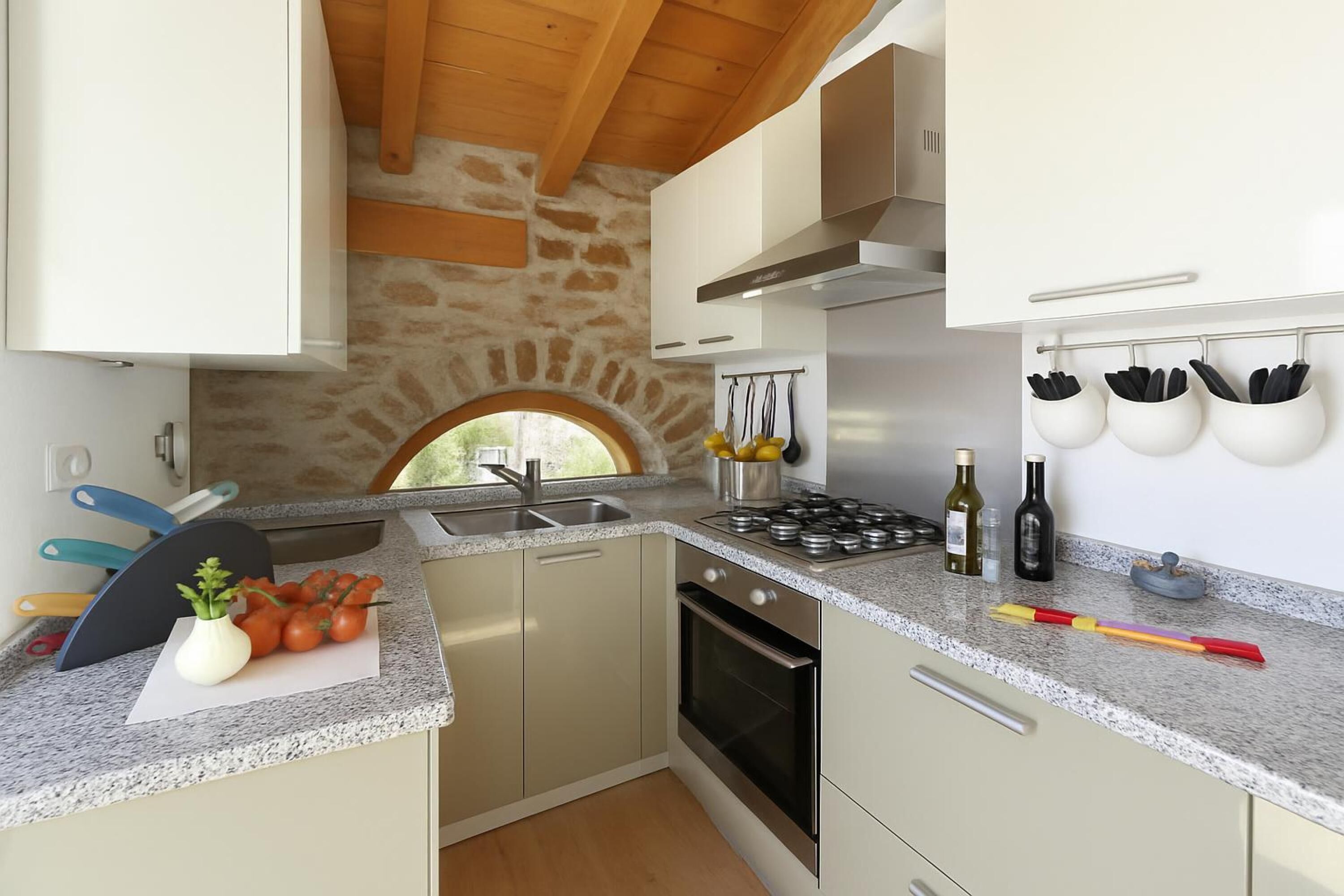 Une cuisine de taille réduite avec un mur en pierre, une fenêtre et un four encastré.