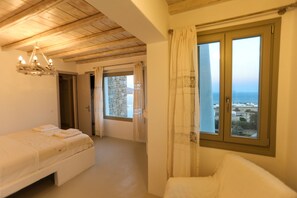 Une chambre à coucher avec un lit, une fenêtre avec des rideaux et une vue sur la mer.