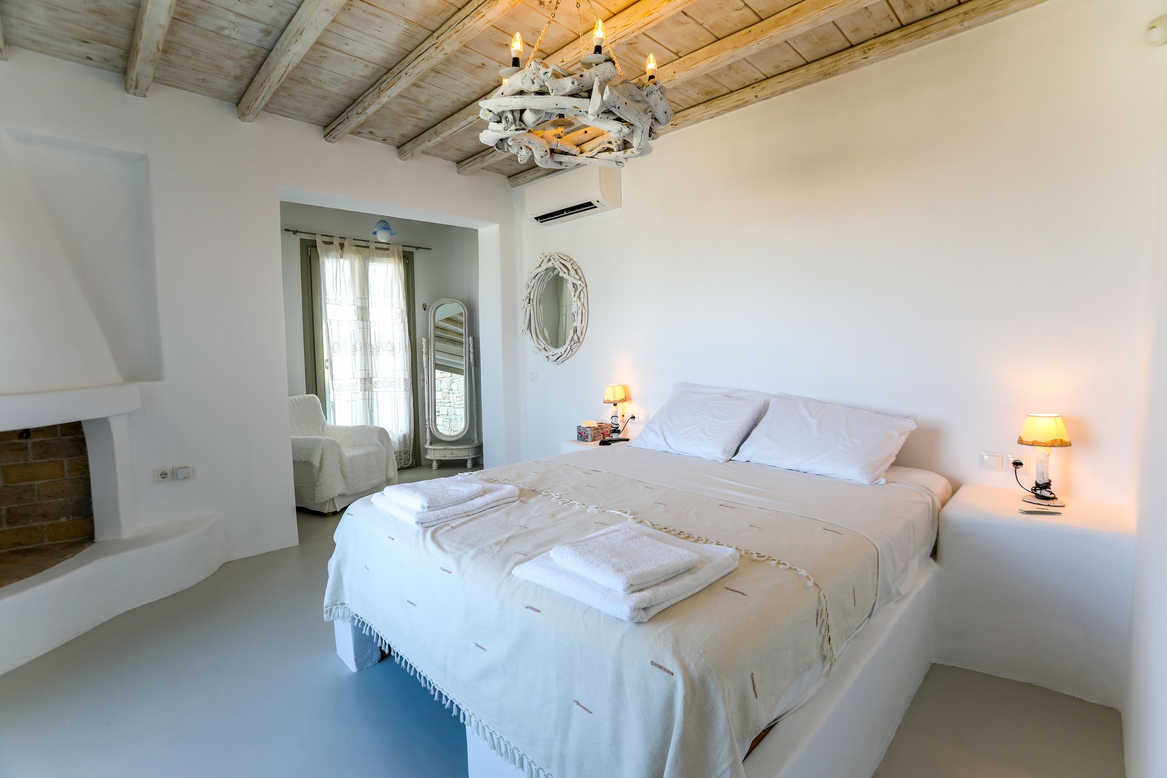 A spacious bedroom with a large bed, a chandelier, and a fireplace.