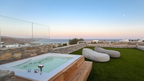 Una terraza en la azotea con jacuzzi, zona de estar y vistas al mar.