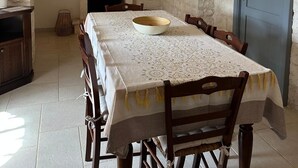 Un comedor con pared de piedra, chimenea y una mesa lista para seis comensales.