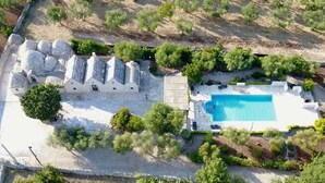 Vista aérea de una propiedad con piscina, estructuras de piedra y vegetación circundante.