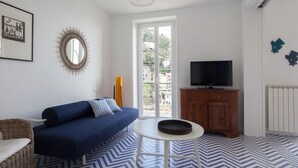Un salon moderne avec un canapé, un téléviseur, une petite table et un sol à motifs.