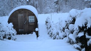 A wooden cabin with a snow-covered roof, surrounded by snow-covered trees and bushes. - Little Sweden, that's what we call the place where the house is located in the High Coast area. (Resele)