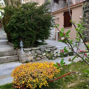 A stone staircase leading to a house with a stone wall and a small garden with yellow flowers. - MURATO STUDIO 2 PEOPLE (Murato)